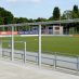 Wellenbrecher im Stadion des HSV Barmbek-Uhlenhorst in Hamburg mit Blick auf das Spielfeld und den Ballfangzaun.