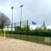 Ballfangzaun an einem Beachvolleyballfeld mit HSV Fahnen im Hintegrund.