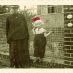 Frohe Weihnachten 2021!
SW-Foto aus den 1930er Jahren von einem Wellengitterzaun in Berlin Pankow. Vor dem Zaun steht eine alte Frau. Neben ihr ein kleines Mädchen mit einer dazu retuschierten roten Weihnachtsmütze.