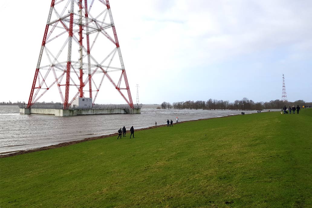 Sturmflut an der Elbe am 30.1.2022 mit Blick über den Deichfuß an der Hetlinger Schanze. Der gesamte Fuß vom Strommast ist von Wasser umgeben.