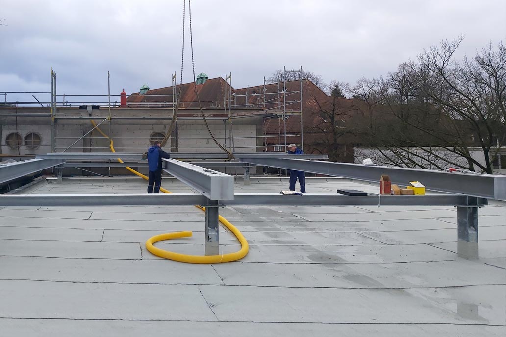 Metallbauer bei der Montage einer Stahlbaubühne auf einem Dach.