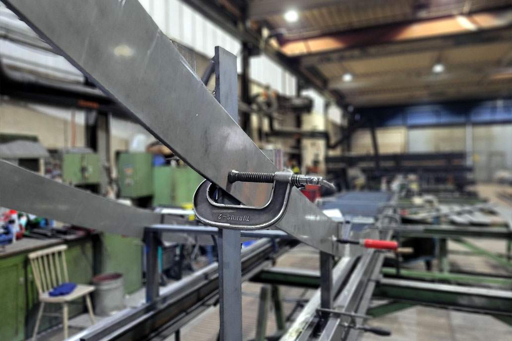 Schraubzwingen halten Brennteile aus Stahl für ein gebogenes Geländer in der Werkstatt des Metallbauers Gawron & Co.