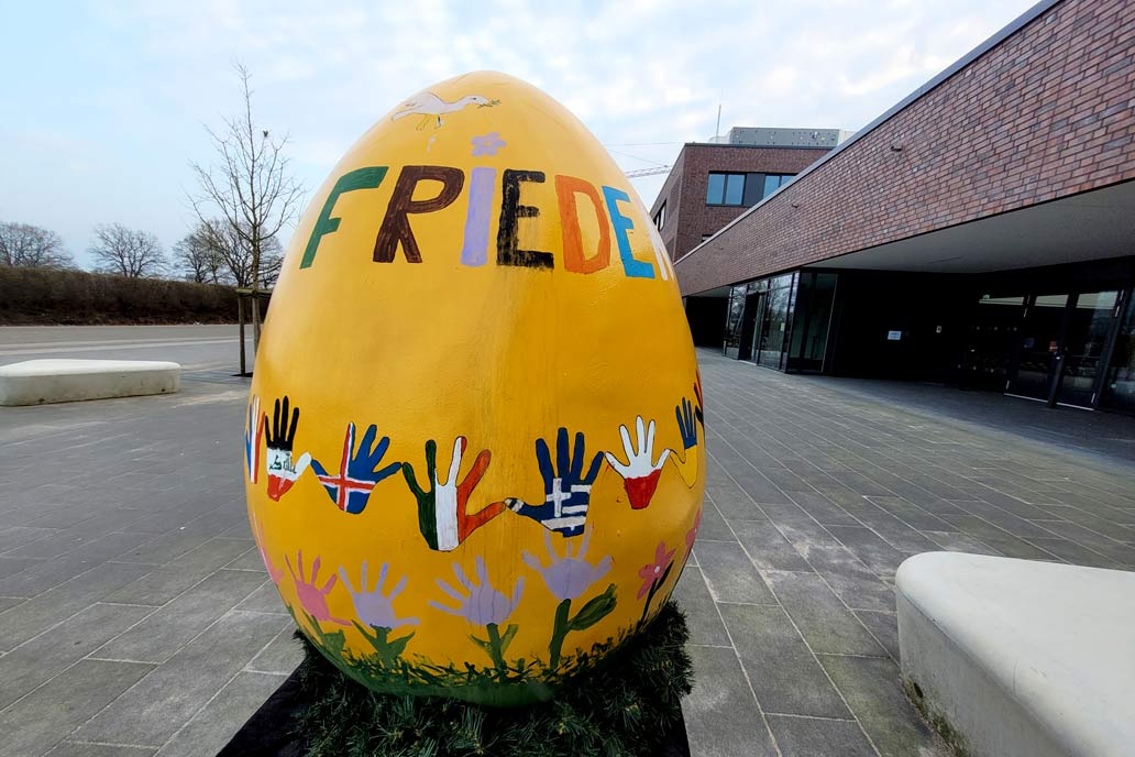 Gelbes Riesen-Osterei bemalt von Schüler:innen der Caspar-Voght-Schule in Rellingen mit dem Spruch "Frieden für die Welt".