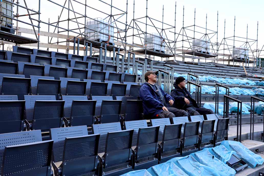 Zwei Metallbauer sitzen auf den von ihnen montierten Stühlen auf der neuen Tribühne der Eutiner Festspiele.