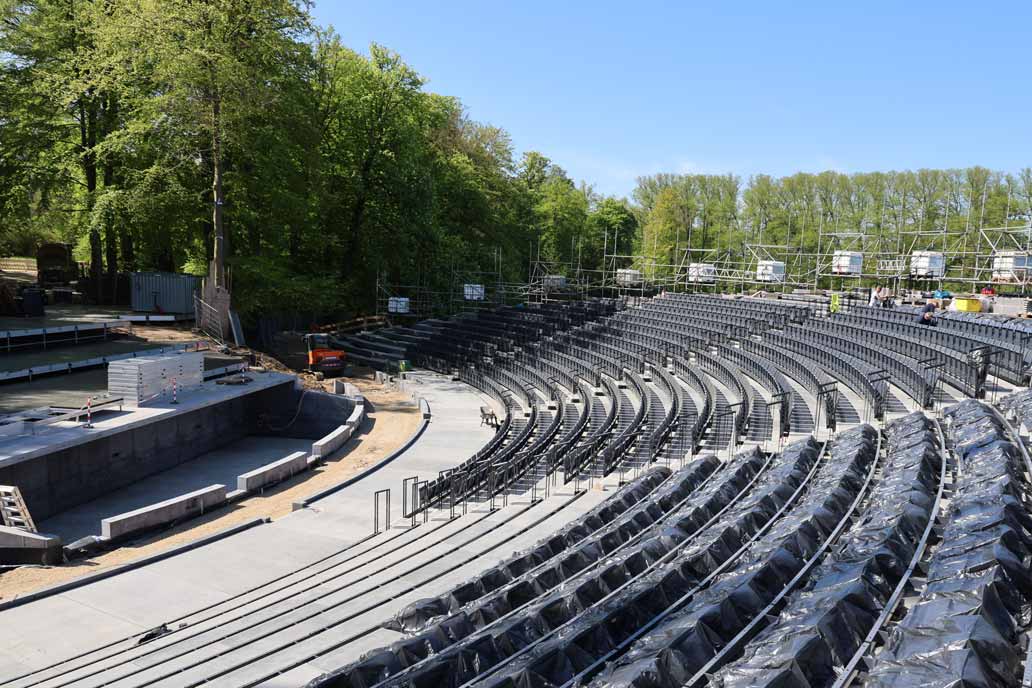 Blick über die Baustelle der Eutiner Festspiele: Links die neue Bühne, rechts die Tribüne mit teilweise montieerten grauen Metall-Stühlen.