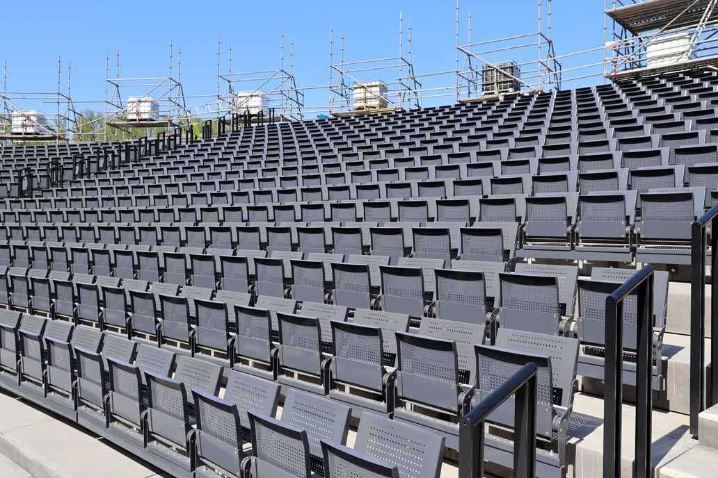 Mehrere Reihen graue Metall Klappstühle auf der neuen Tribüne der Eutiner Festspiele.