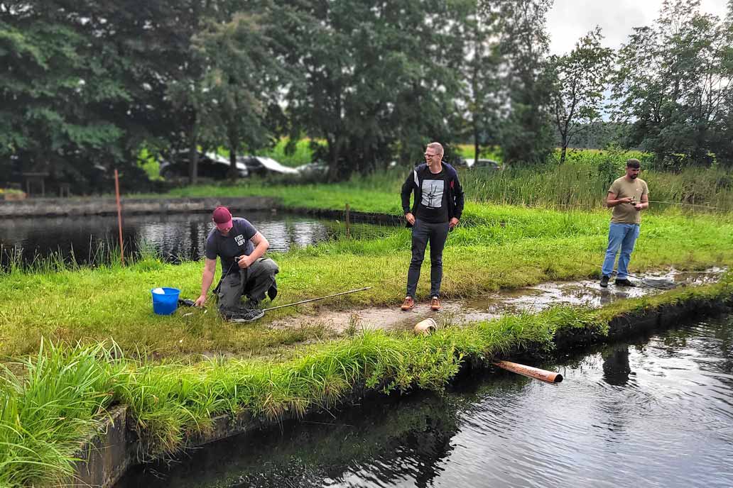 Zwei Angler und ein dritter Kollege, der lachend in der Mitte steht.