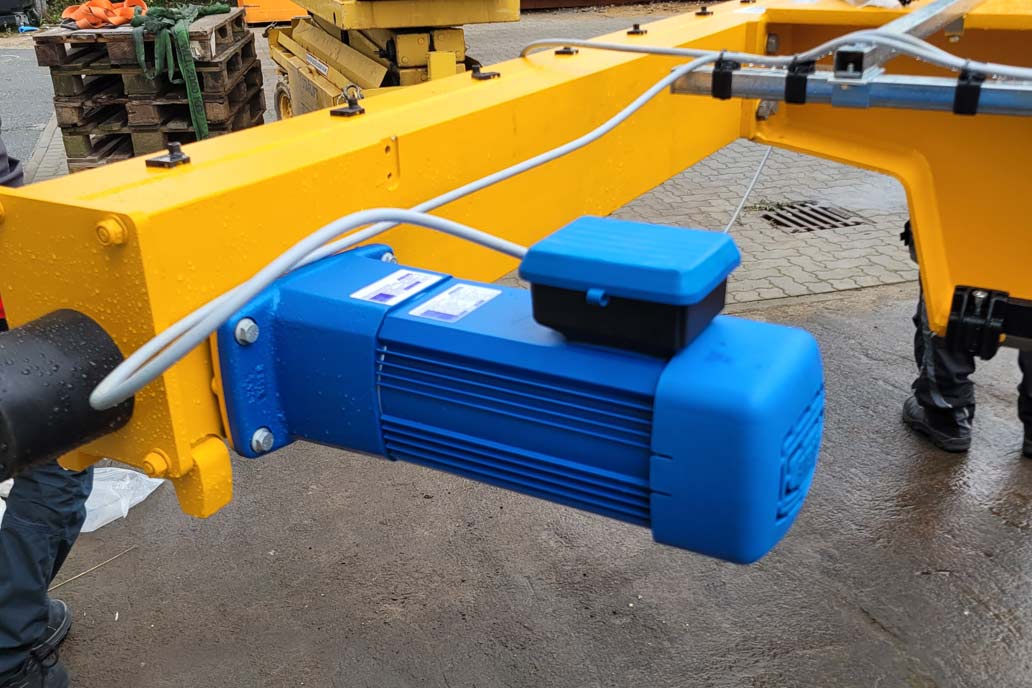 Der blaue Kranfahrantrieb von einem unserer neuen Brückenkrane an dem orange-gelben Hauptträger des Hallenkrans.