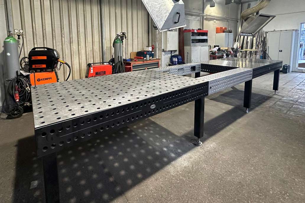Ein dunkelgrauer Schweißtisch mit Löchern zur Befestigung von Metallbauteilen in der Edelstahl-Werkstatt von Gawron.