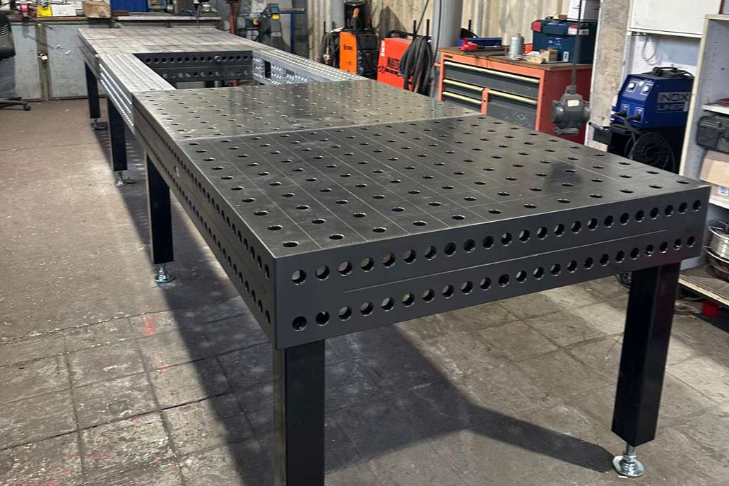 Ein dunkelgrauer Schweißtisch mit Löchern zur Befestigung von Metallbauteilen in der Edelstahl-Werkstatt von Gawron.
