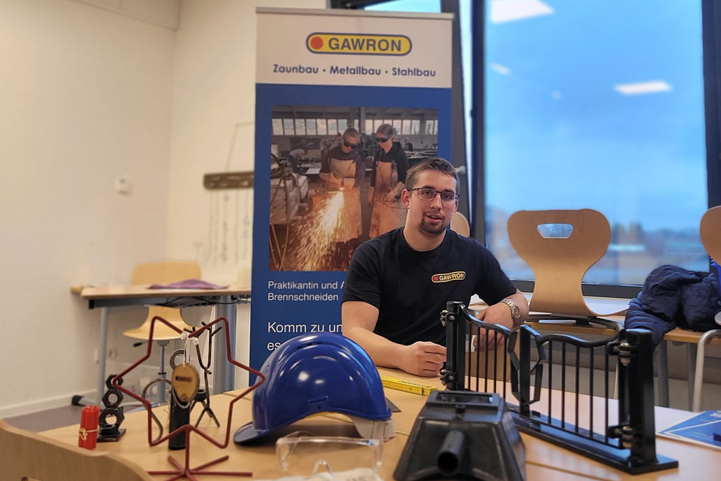 Ein Schlosser von Gawron sitzt vor einem Rollup an einem Tisch beim Berufe-Speed-Dating in der Caspar-Voght-Schule in Rellingen.