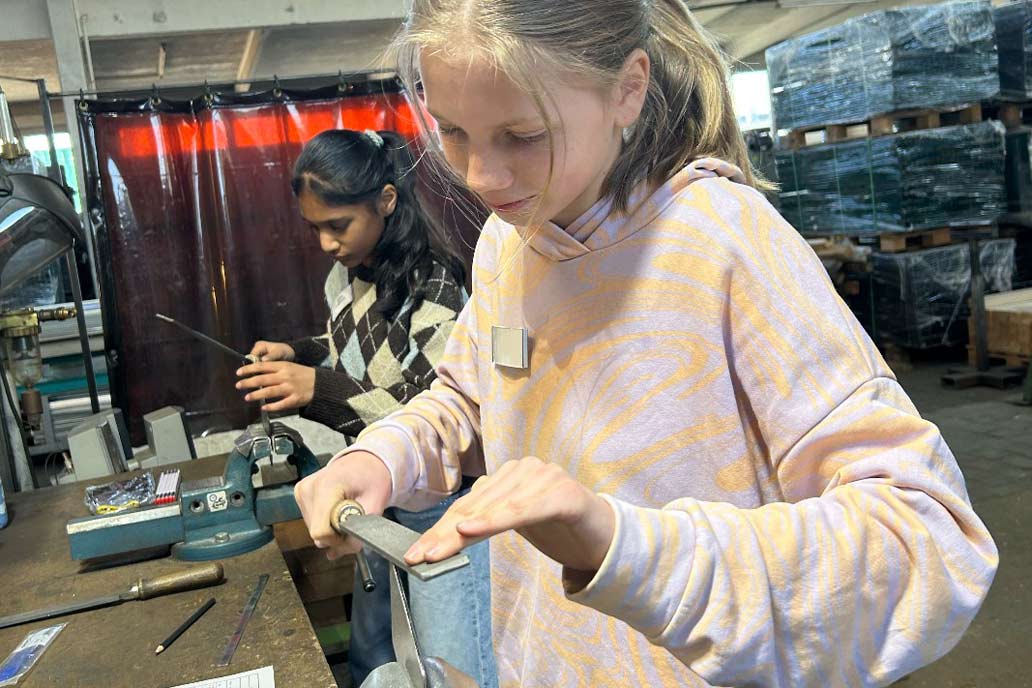 Zwei Mädchen feilen ein Stück Metall an der Werkbank beim Girls'Day 2025 bei Gawron in Rellingen.