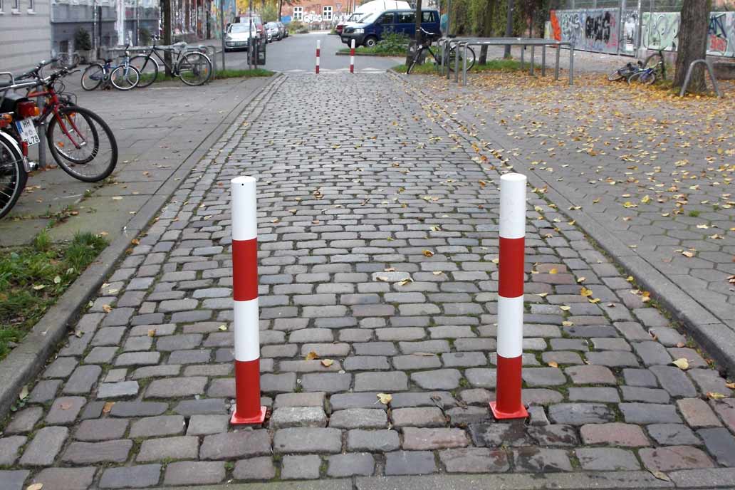 Zwei rot-weiße runde Poller als Straßenabsperrung.